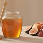 Glas goldener Honig mit Holzlöffel neben einer Schale Zuckerwürfel und frischem Obst